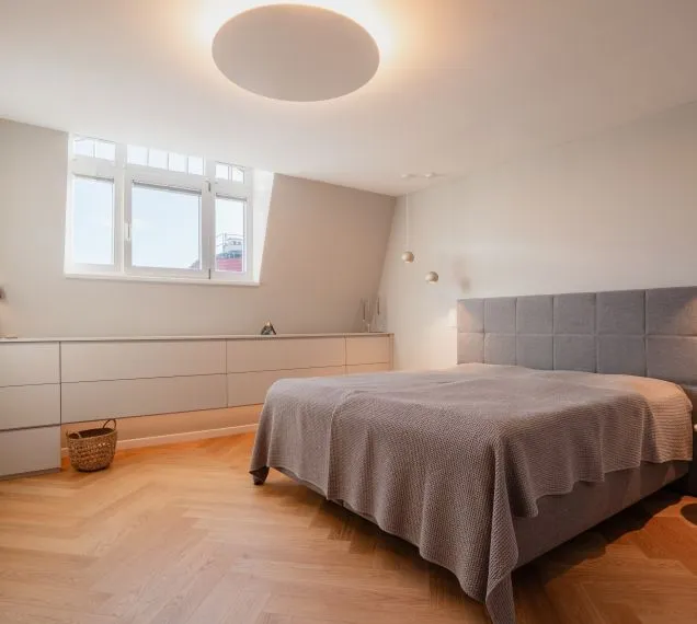 Schlafzimmer unter der Dachschräge mit Bett und Schrankwand